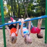 kids hanging upside down on monkey bars